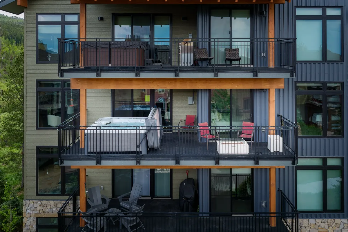 A view of balconies and an outdoor hot tub area, complete with seating and mountain vistas. The scene suggests a communal space for socializing and enjoying sunsets.