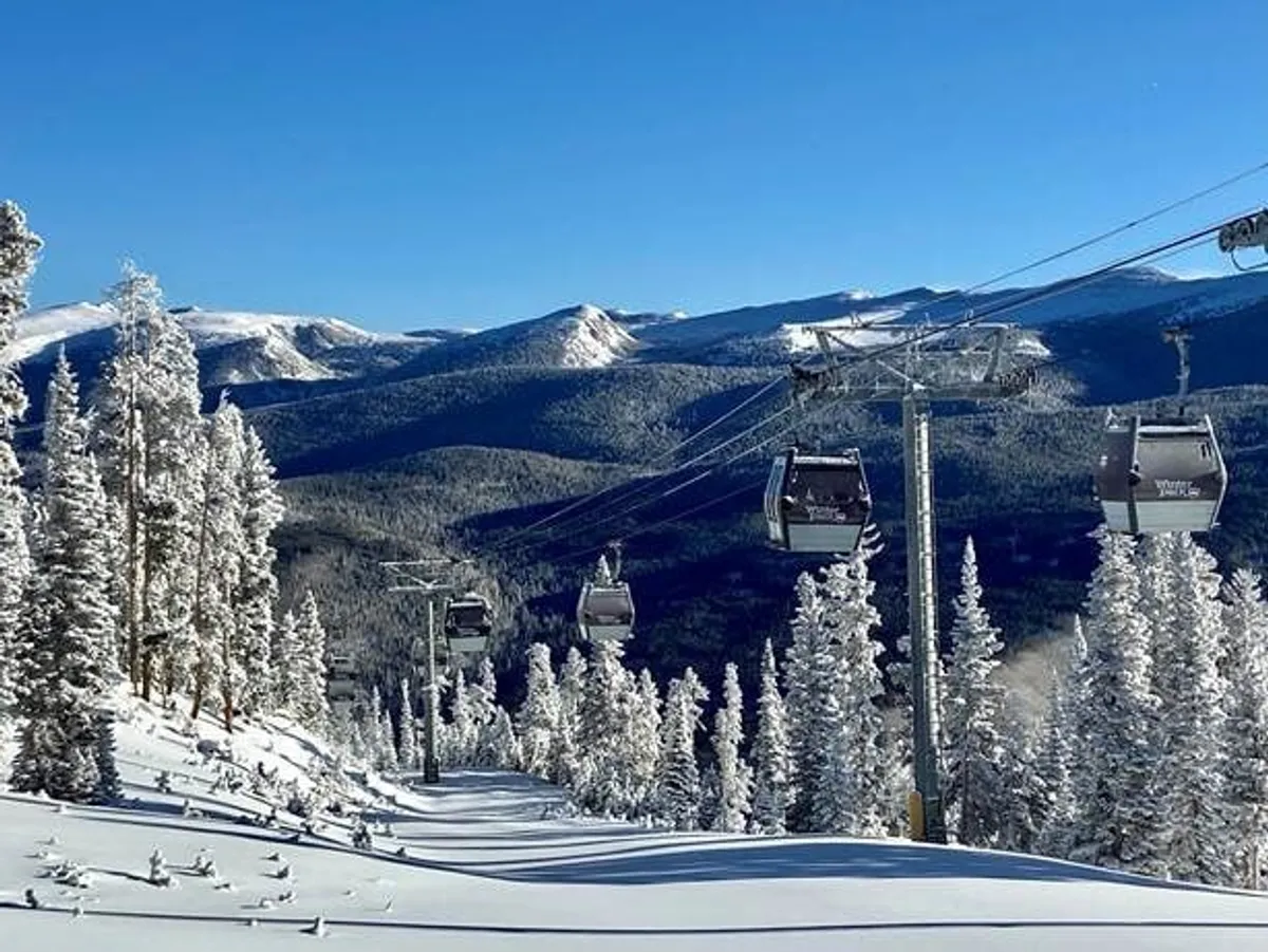 A breathtaking exterior shot capturing snow-covered ski slopes, a ski lift ascending the mountain, snowy pine trees, and a majestic mountain range in the distance. The scene is alive with adventurous potential, illustrating the thrill of skiing and snowboarding in a pristine alpine environment.