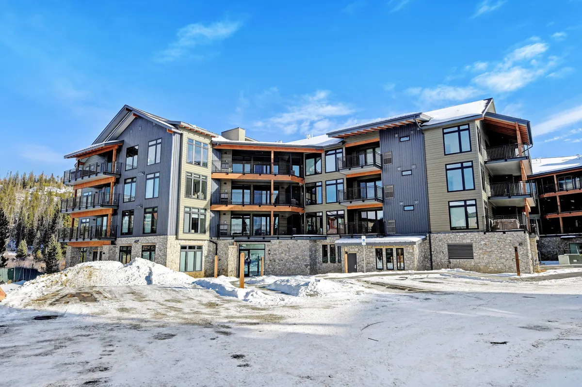 A contemporary exterior shot of the property showcasing modern architecture, balconies, and snow-covered ground. The image hints at both the comfort of home base and the adventurous environment, with visual cues for skiing, snowboarding, and mountain hiking.